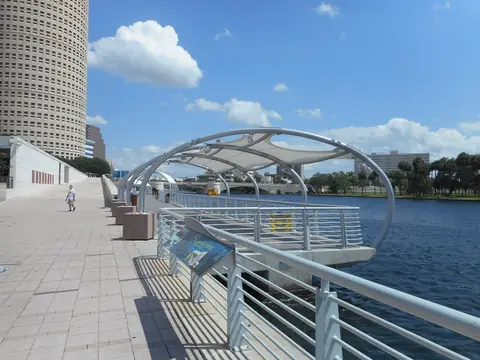 The Tampa Riverwalk under its white shade canopy beside the river