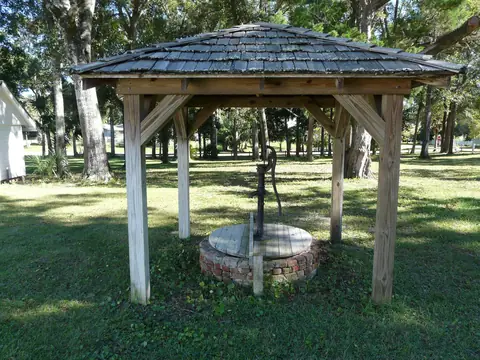 A hand-pump well under a shingled shelter on a green lawn at Orman House, Apalachicola, Florida