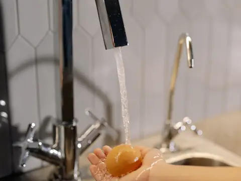 Water running from a chrome kitchen faucet, a separate small tap beside it