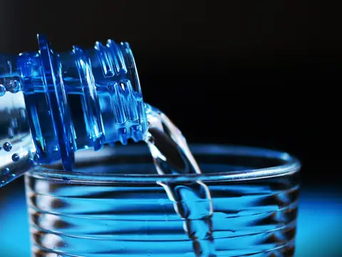 Water poured from a bottle into a clear glass