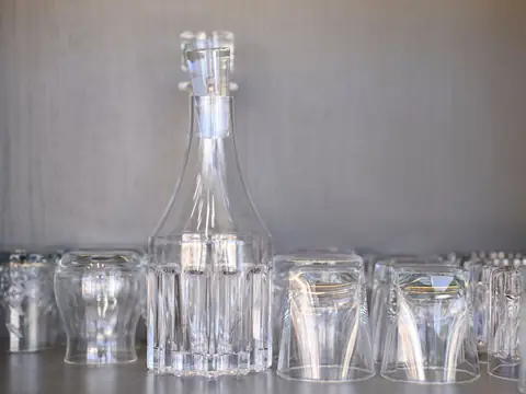 A glass decanter among clear upturned drinking glasses