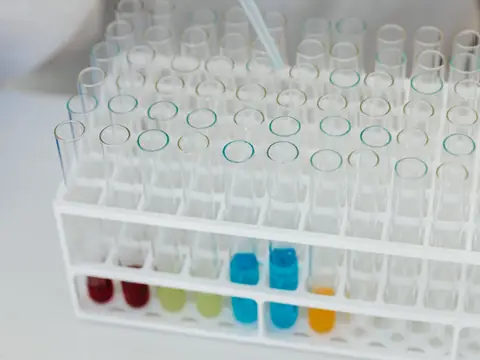 A white rack of glass test tubes, a few holding colored samples