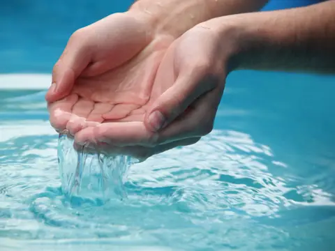 Hands scooping clear blue water