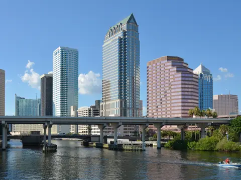 The Hillsborough River in Tampa on a clear day, downtown towers behind a bridge